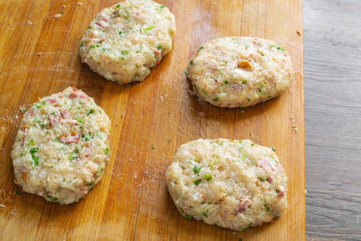 Четыре сформированные сырые куриные котлеты с краковской колбасой на доске