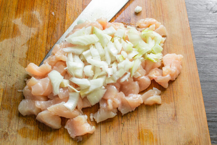 Измельченный репчатый лук, выложенный поверх кусочков куриного филе