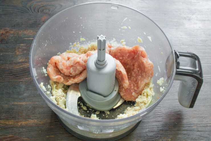 Куриный фарш с луком и чесноком в чаше блендера для приготовления начинки