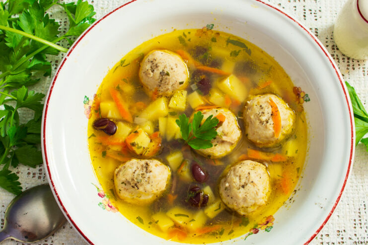 Куриный суп с фасолью и фрикадельками в тарелке со свежей зеленью