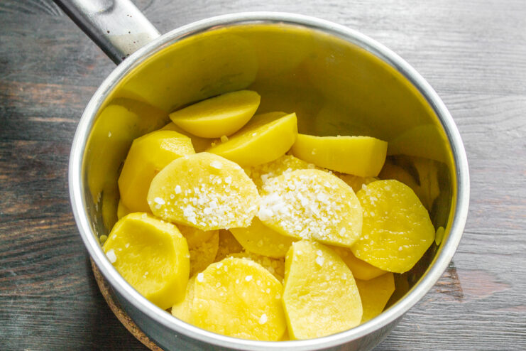 Нарезанный картофель в кастрюле с солью