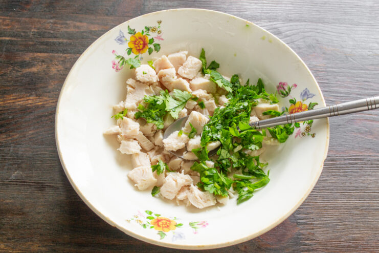 Добавление измельченной свежей кинзы к нарезанной курице