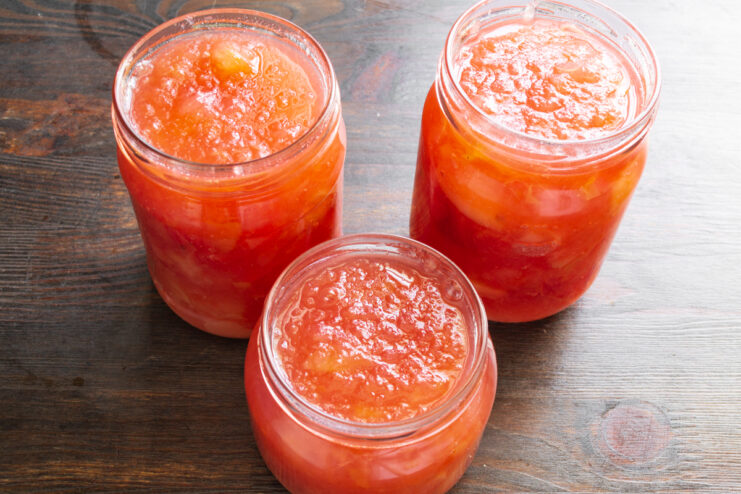 Фасовка варенья по банкам Горячее яблочное варенье-желе разлито по стеклянным банкам