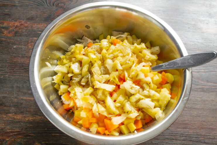 Кубики маринованных огурцов в миске с салатом