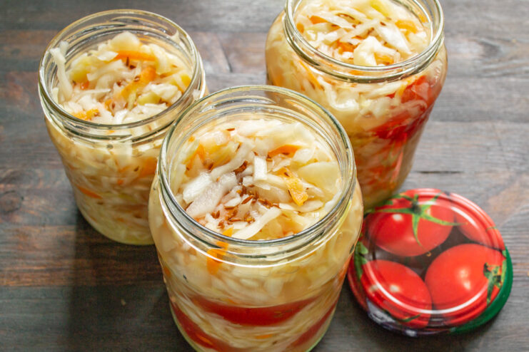 Квашеная капуста с помидорами, разложенная по стеклянным банкам