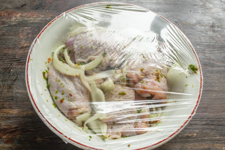 Маринование курицы в холодильнике Миска с курицей и луком под пищевой пленкой для маринования