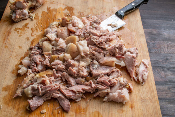 Измельчение мяса и кожи рульки Нарезанное вареное мясо свиной рульки на разделочной доске