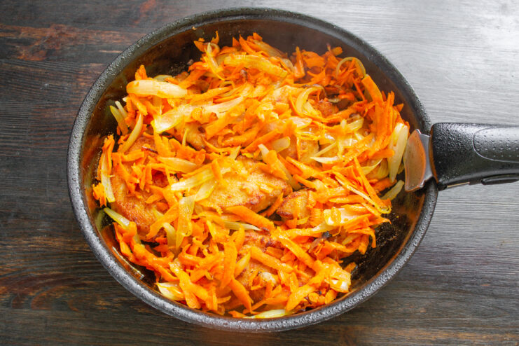 Обжаренная куриная грудка, покрытая слоем тушеной моркови и лука