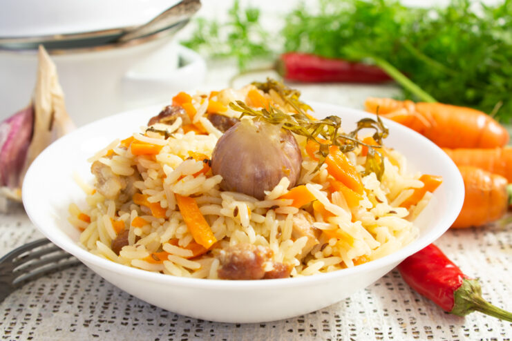 Рассыпчатый плов со свининой и чесноком в глубокой тарелке