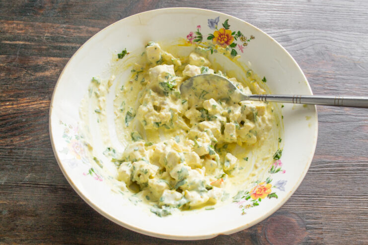 Тщательно перемешанный куриный салат с зеленью и куркумой
